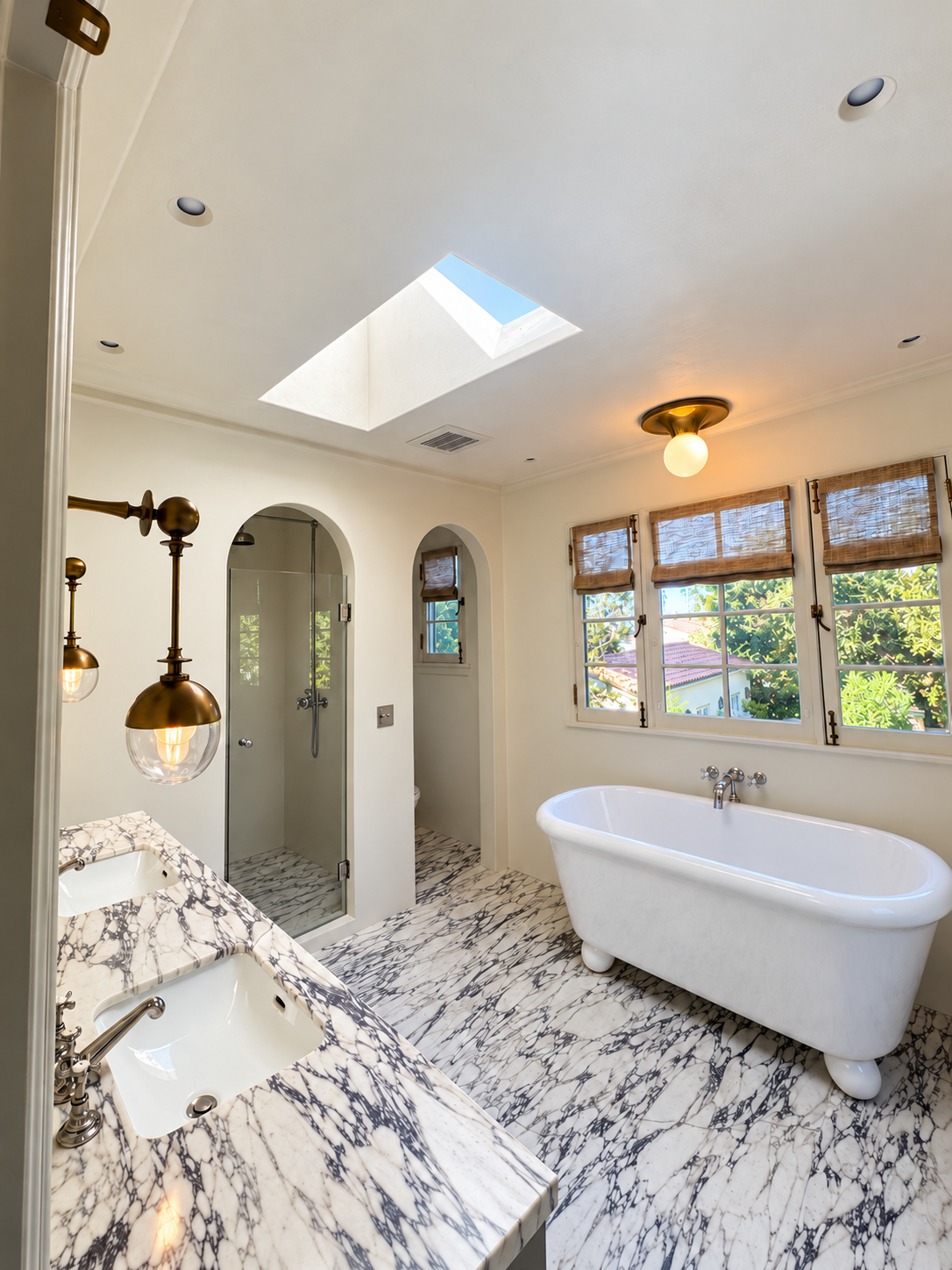 Full bathroom with a glass shower, freestanding bathtub, double vanity and skylight.